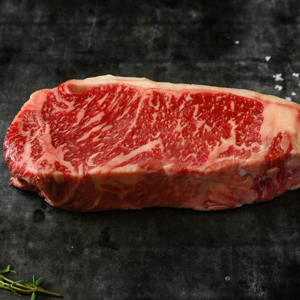 Raw new york steak with marbling on a dark surface